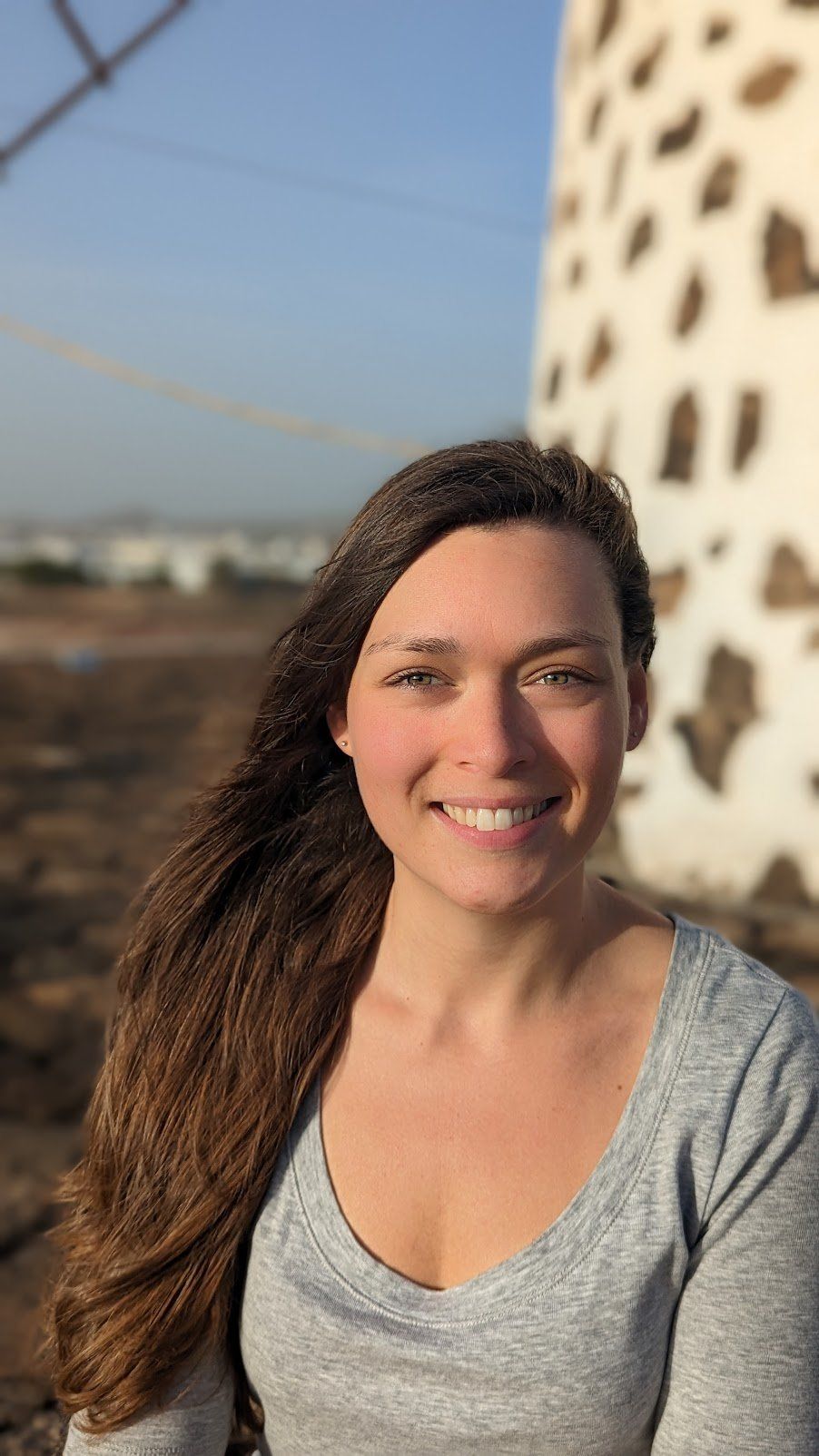 Retrato de Judy Turcotte, trabajadora social, sonriente bajo la luz dorada del atardecer, paisaje de las Islas Canarias al fondo